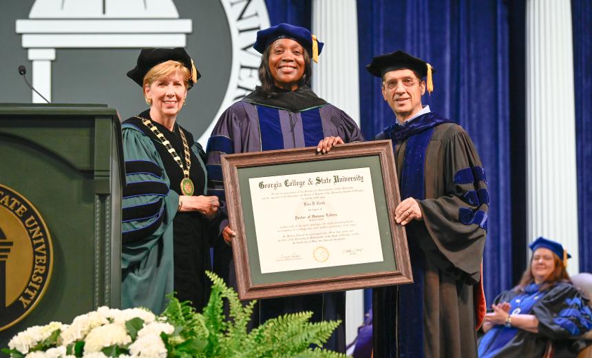 Dr. Lisa Cook, President Cox, and Provost Spirou pose for a photo holding Dr. Cook's Honorary Doctorate degree.