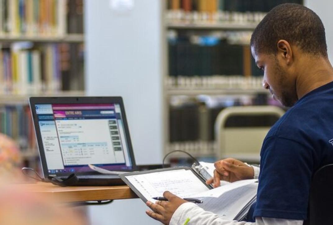 student in library at laptop