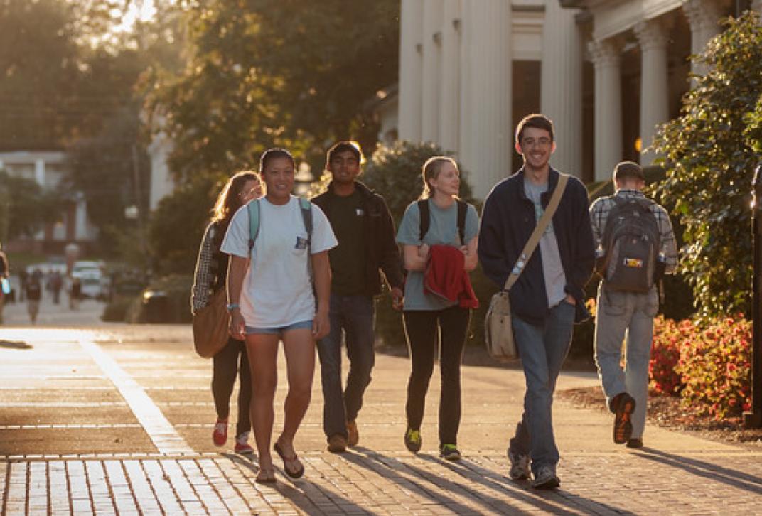 students walking down the sidewalk in front of Bell Hall