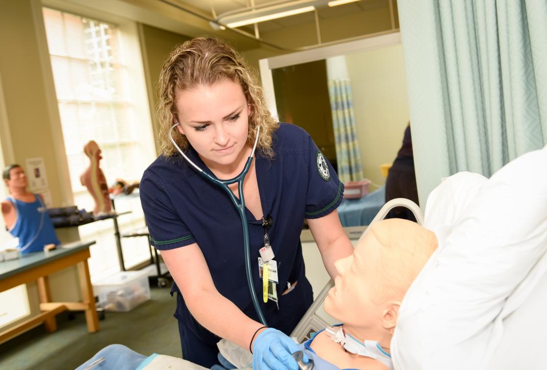 Nursing student practicing clinical skills on a SIM Manikin