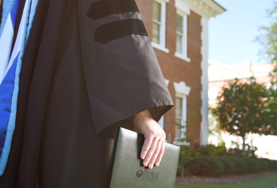An anonymous graduate holds a diploma cover.