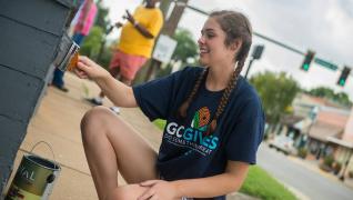 student painting a building on gc gives day