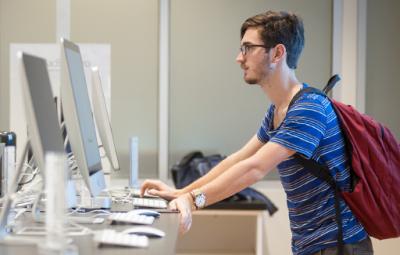 student standing at desktop computer