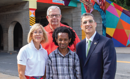 Artist Abraham Abebe stands with Provost Costas Spirou and Macon Transit Authority's Jami Gaudet in front of a mural