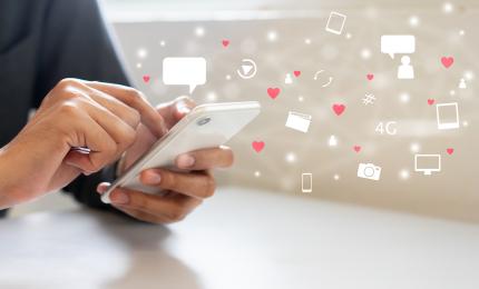 A person scrolling on a phone while social media icons such as hearts and followers appear in the background