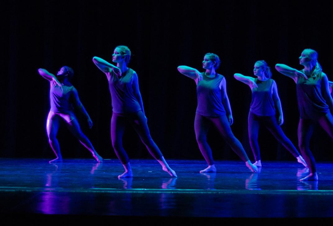 dancers in formation on dark stage
