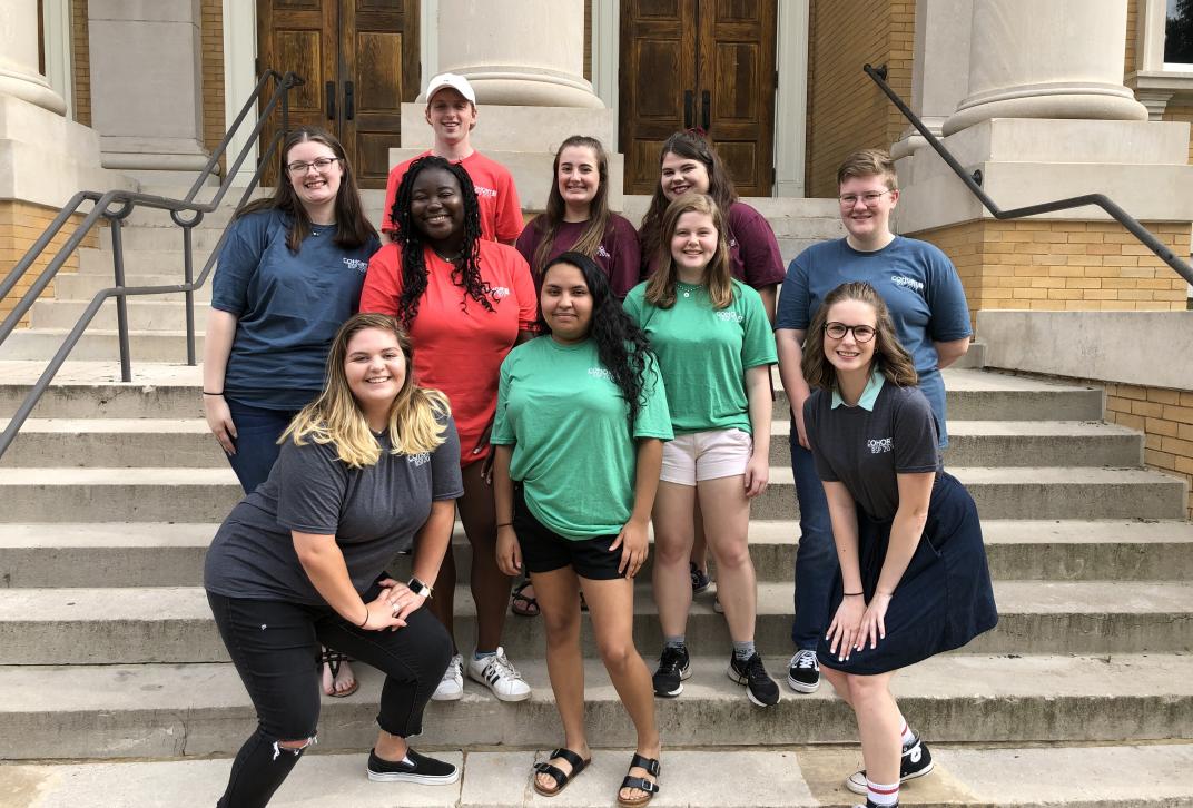 Bridge student staff pose for a photo on the steps of the Magnolia Ballroom building