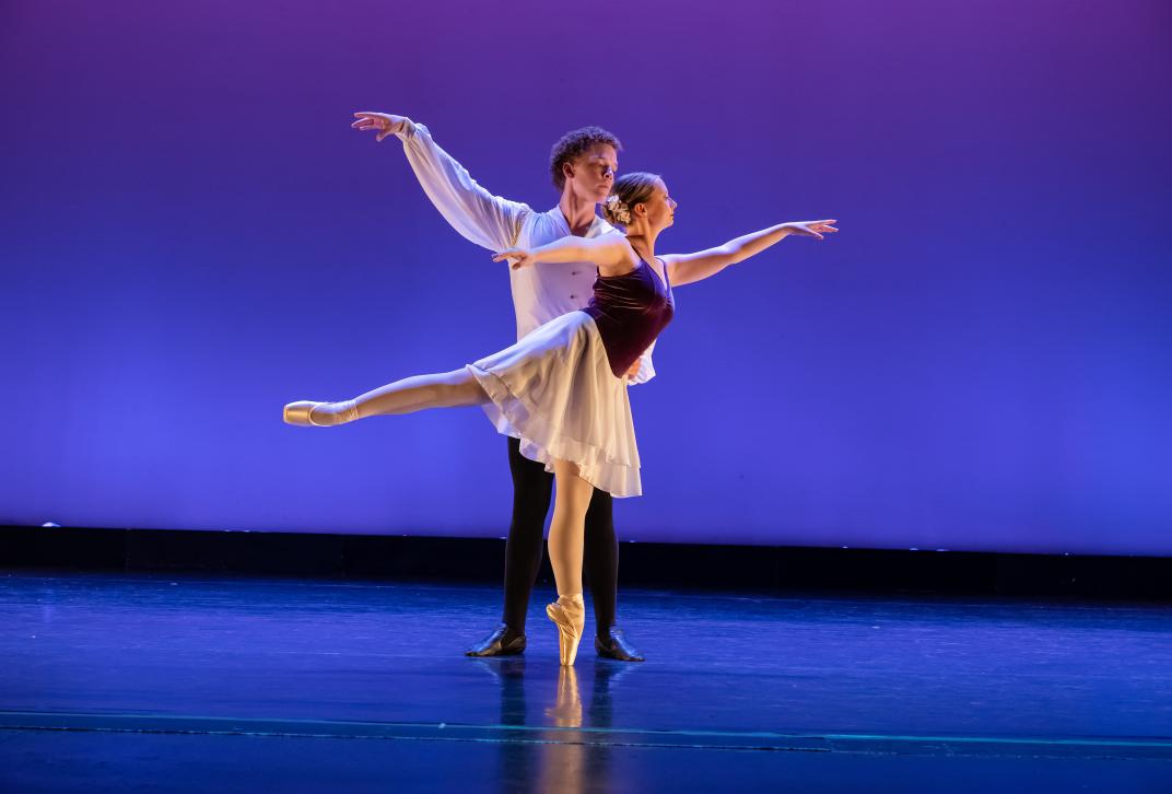 Male and female dancers move gracefully in a pas de deux.