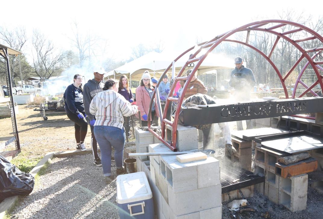 people standing near a grill at a farm