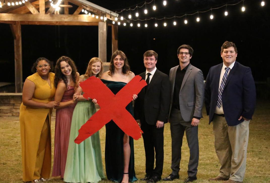 Students pose for a photo with an x-shaped prop