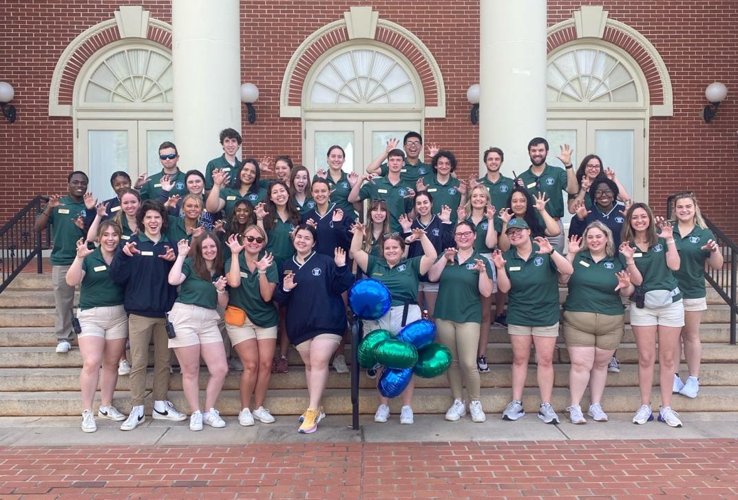 The Council of Student Ambassadors pose on the steps of Russell Auditorium with their green polos on and paws up!