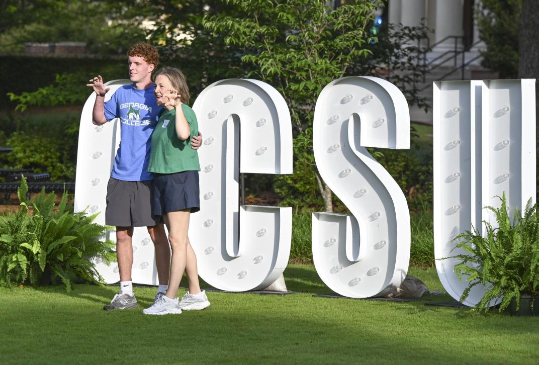 Parent and student posing in front of GCSU letters on Front Lawn.