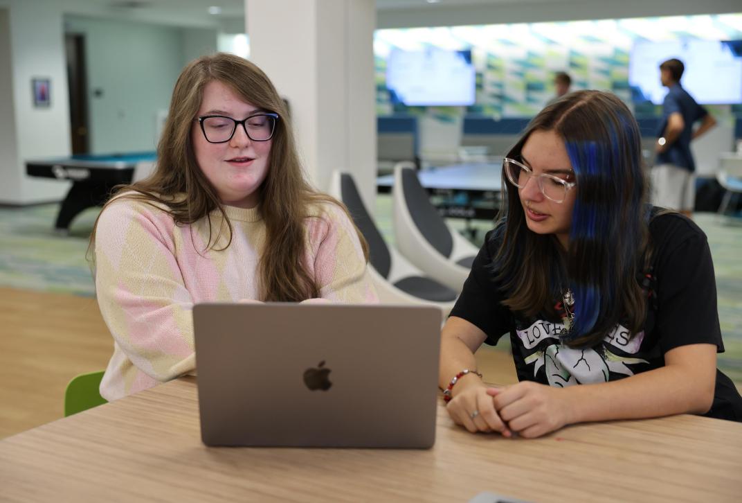 Two students working together on a laptop