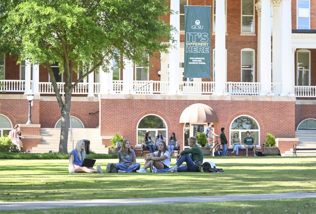 Students sitting outside on the lawn on Front Campus at GCSU