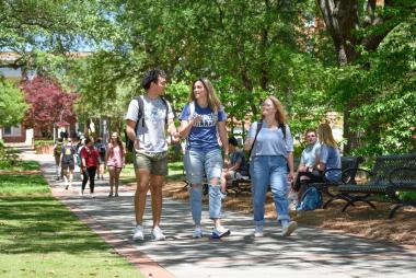 Students walking down a sidewalk on a college campus