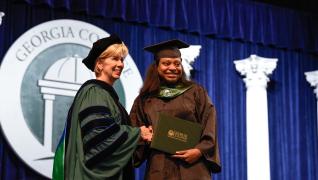 Preident Cox shakes student's hand at Commencement