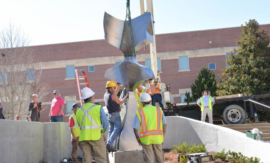 workers raising a sculpture