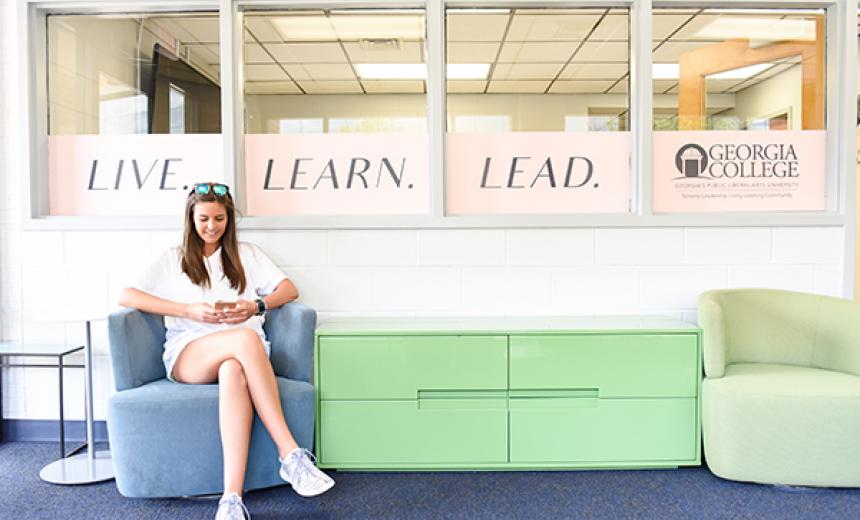 student in chair with live, learn, lead banner
