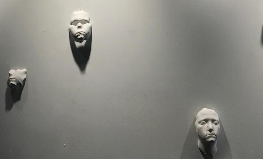white sculptures of faces on white wall