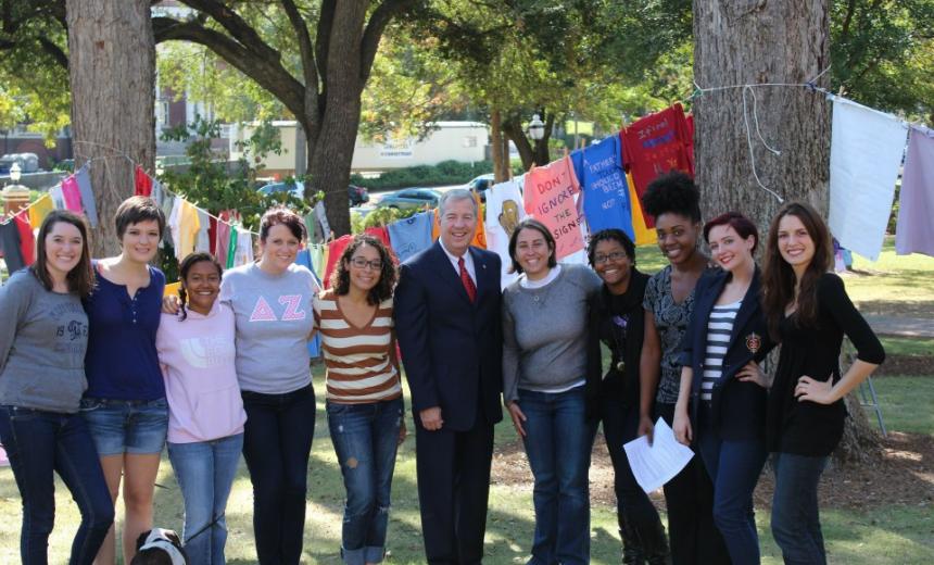 Staff of the Women's Center stand with Dr. Dorman in front of the Clothesline Project display. 