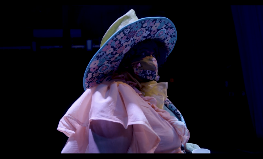 The Mad Hatter stands wearing an eccentric hat and colorful outfit