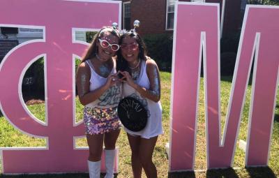 sisters in front of cut out sorority letters