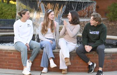 Students sit and laugh around a fountain