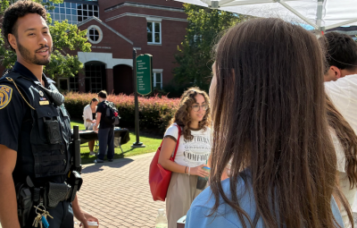 A public safety officer speaking to students at a table set up on campus