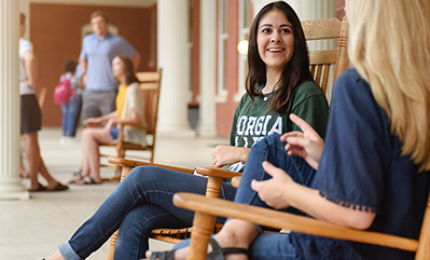 Students visiting in rocking chairs on front porch.