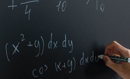 A person solves a math problem on a blackboard