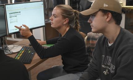 Stwo students work on a finance program on a computer in the Bobcat Trading Room