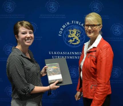 Audrey Waits recieving book and certificate from Fulbright Finland officer